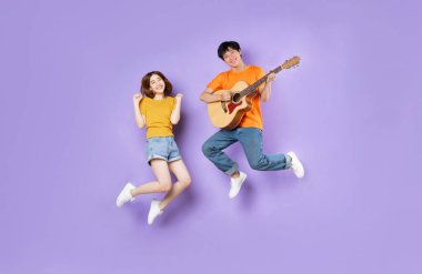 Zıplayan bir çiftin portresi, mor arka planda izole edilmiş.