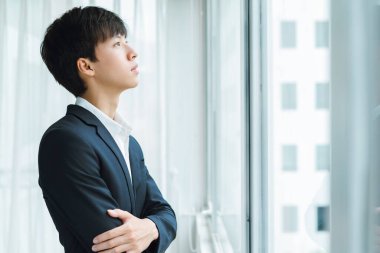 pencereden dışarı bakan bir adam bir takım elbise içinde