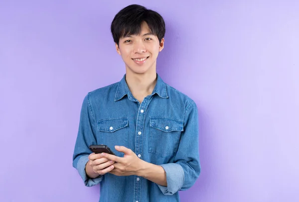 紫色の背景にポーズをとった青いシャツのアジア人男性の肖像 — ストック写真