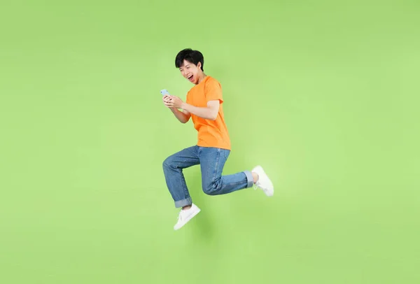 Asian Man Jumping Holding Smartphone Isolated Green — Stock Photo, Image