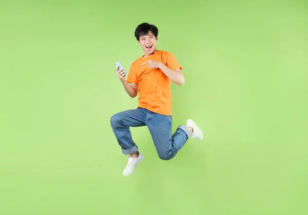 Asian Man Jumping Holding Smartphone Isolated Green — Stock Photo, Image