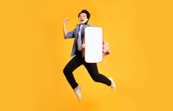 Image Jumping Asian Man Holding Smartphone Hand Isolated Yellow Background — Stock Photo, Image