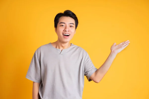 黄色い背景をしたアジア系の若者 — ストック写真