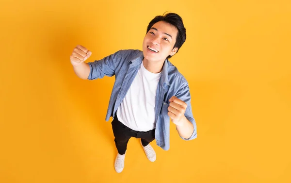 黄色の背景にポーズをとるアジア系男性のイメージ — ストック写真