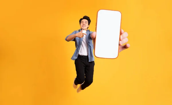 Image Jumping Asian Man Holding Smartphone Hand Isolated Yellow Background — Stock Photo, Image