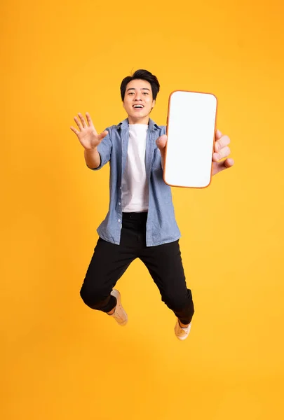 Immagine Saltare Asiatico Uomo Tenendo Smartphone Mano Isolato Sfondo Giallo — Foto Stock