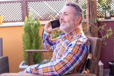 Gülümseyen olgun bir adam telefonda konuşuyor.