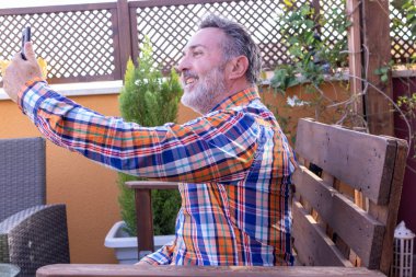 Olgun adam cep telefonuyla video görüşmesi yapıyor.