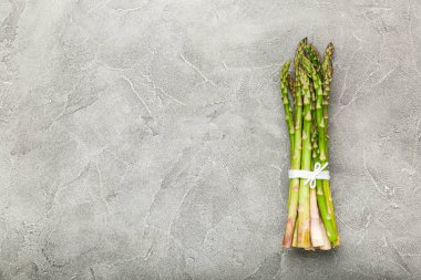 Beton arka planda bir sürü yeşil kuşkonmaz. Üst görünüm, alanı kopyala