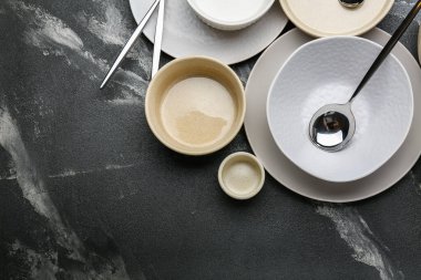 Gri zemin üzerinde çatal bıçak takımı ve bardak olan bir sürü boş tabak.