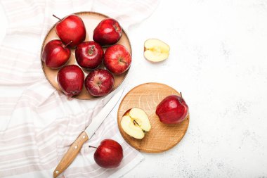 Taze olgun ve dilimlenmiş kırmızı elmalar kesme tahtası ve bıçakla taş masada.