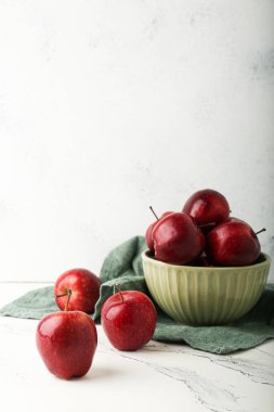 Taze kırmızı elmalar bir tabakta taş bir masada.