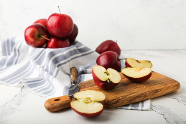 Taze olgun ve soyulmuş kırmızı elmalar kesme tahtası ve bıçakla taş masada.