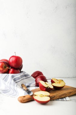 Taze olgun ve soyulmuş kırmızı elmalar kesme tahtası ve bıçakla taş masada.