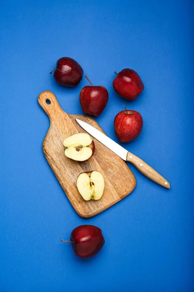 fresh apples and cutting board on blue background .Top view