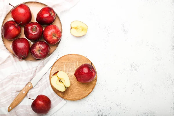 Fresh ripe whole and sliced red apples with cutting board and knife on stone table