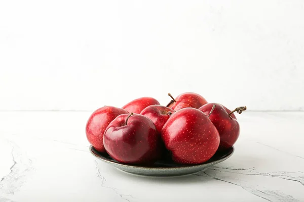 fresh red apples in a plate on a stone table