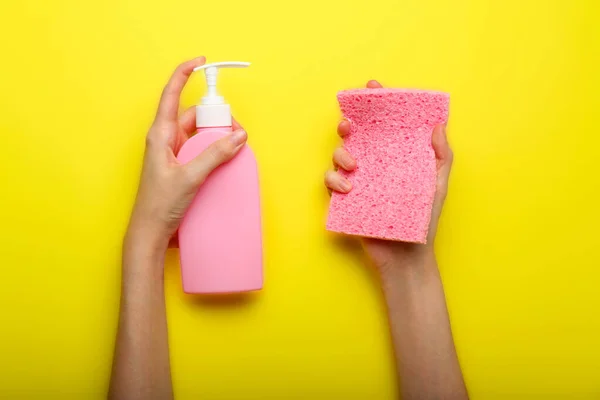 liquid soap and sponge in hands on a yellow background .Cleaning concept