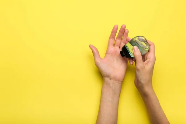 antiseptic applied to hands on yellow background