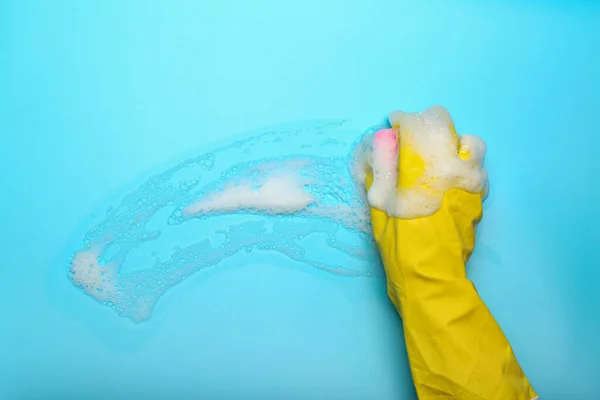gloved hand with washcloth and foam on blue background