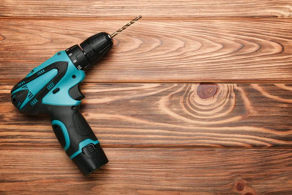 cordless screwdriver on a wooden background top view with free space for text