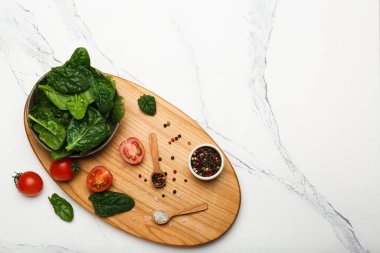 Tahta kesme tahtasındaki domatesli biber ve tuzlu ıspanak kasesinde. Beyaz arkaplan, üst görünüm