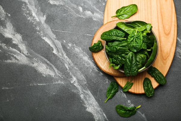 Organic food concept with spinach leaves in bowl on black background top view copy space