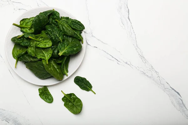 spinach leaves in a bowl on a white background top view