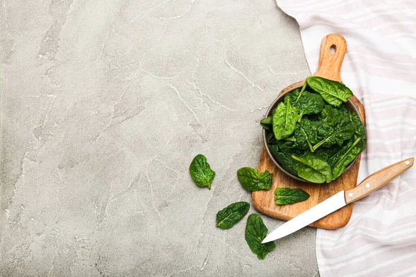 Organic food concept with spinach leaves in a bowl on a cutting board gray background top view copy space