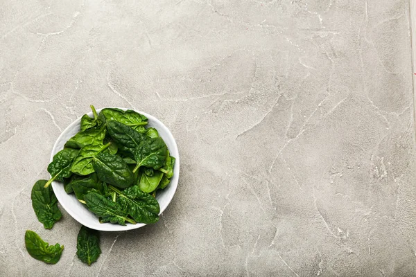 spinach leaves in a bowl on a gray background top view copy space