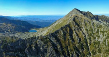 Taul Tapului Buzulu 'nun dikey hava aracı manzarası. Göl, Retezat Dağları 'nın yüksek tepelerinin altında, dağ çam ağaçlarıyla dolu bir alp kazanın içinde duruyor. Carpathia, Romanya.