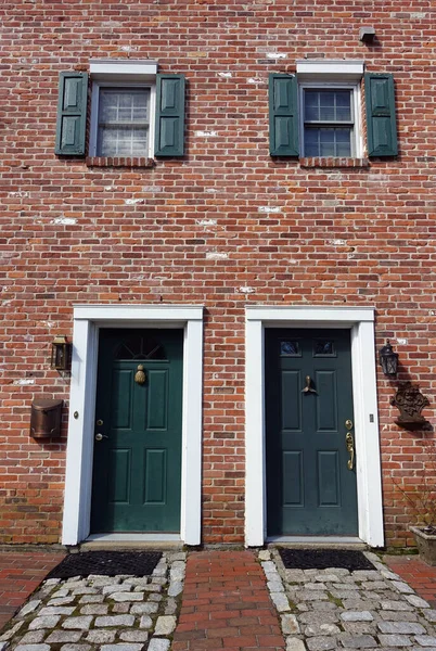 Two Green Doors Side-by-Side in an Historic Brick Building with Stone Walkways