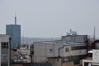 Gri ve düz binalar. Arka planda puslu bir piç.