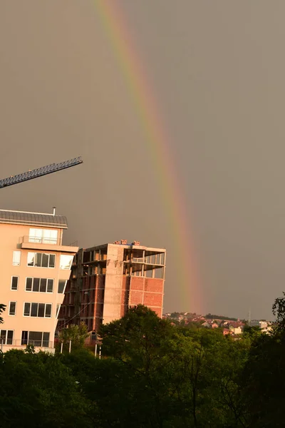 After the rain, a rainbow appeared and the sun\'s rays illuminated the cityscape