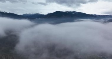 Dağlık bir kasabanın ve yolların sisli hava görüntüleri. Yavaşça sola hareket ediyor.