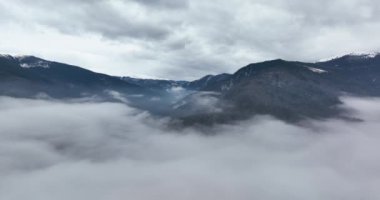 Sis ve bulutlarla dağlarda sonbahar günbatımının havadan görünüşü. Sinematik çekim