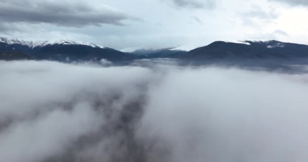 Langzaam bewegende filmische drone schot op de top van een dichte mist en bergen — Stockvideo