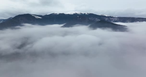 Een 5.1k drone video vliegend door een laag mist met uitzicht op de bergen op de rug — Stockvideo