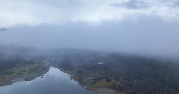 Mystický výhled na jezero, les a město pokryté mlhou. Pozadí hory — Stock video