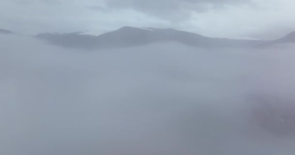 O drone moveu-se para cima revelando as montanhas e o lago. Debaixo do nevoeiro — Vídeo de Stock