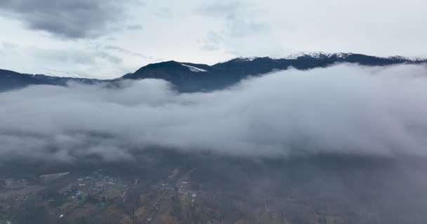 Voando para trás através de nuvens entre montanhas cobertas de neve. Paisagem aérea — Vídeo de Stock