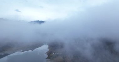 Bir gölün, ormanın ve sisle kaplı bir şehrin mistik manzarası. Arkaplan Dağı