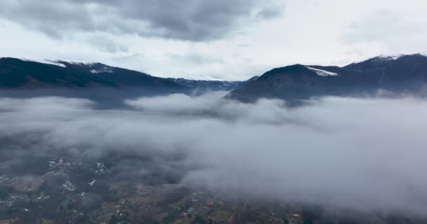 Terugvliegend door wolken tussen besneeuwde bergen. Luchtlandschap — Stockvideo