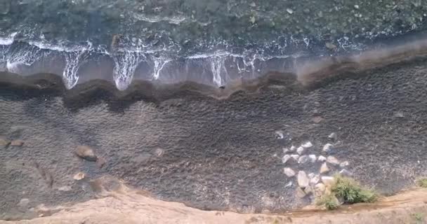 Беспилотник сбит, глядя вниз на волны, надвигающиеся на пляж с черным песком в Кап-дагде. — стоковое видео