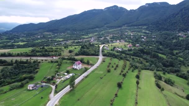 Imagens de drones aéreos avançando para uma aldeia rural perto de montanhas — Vídeo de Stock