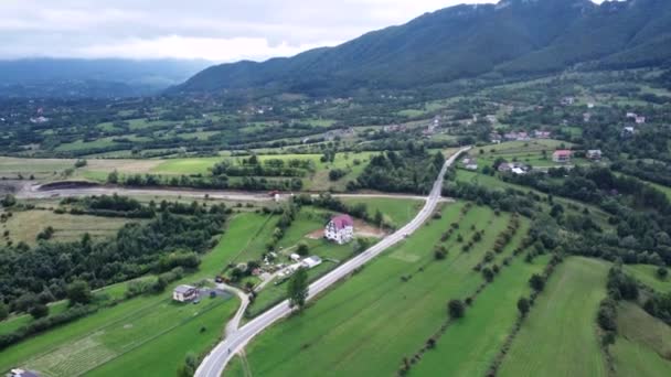 Drone footage of cars, mountain, houses and wide open field in the morning — Stock videók