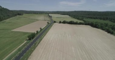 Yeşil tarlalar ve kuru, tepeler, bitkiler ve dağlarla çevrili. Bir araba geçiyor. Yüksek kaliteli 4K DJI Phantom 4 PRO görüntüleri Mayıs 2020 'de Güney Fransa' da çekildi