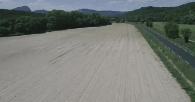 Yeşil tarlalar ve kuru, tepeler, bitkiler ve dağlarla çevrili. Bir araba geçiyor. Yüksek kaliteli 4K DJI Phantom 4 PRO görüntüleri Mayıs 2020 'de Güney Fransa' da çekildi