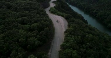 Tek araba, göl ve dağa yakın küçük bir Fransız köy yolunda gidiyor. Haziran 2020 'de DJI Phantom 4 PRO görüntüleriyle yüksek kaliteli 4k dosyalanmış