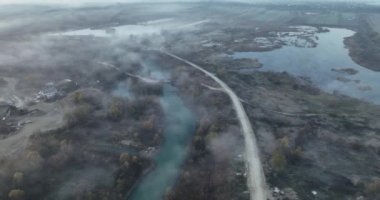 Dağ yolunun havadan görünüşü, sinematik sisli bir nehir ve kırsal bir yol. Ağustos 2021 'de Romanya' da çekilen en kaliteli 4K DJI Mavin 35.1 km görüntü